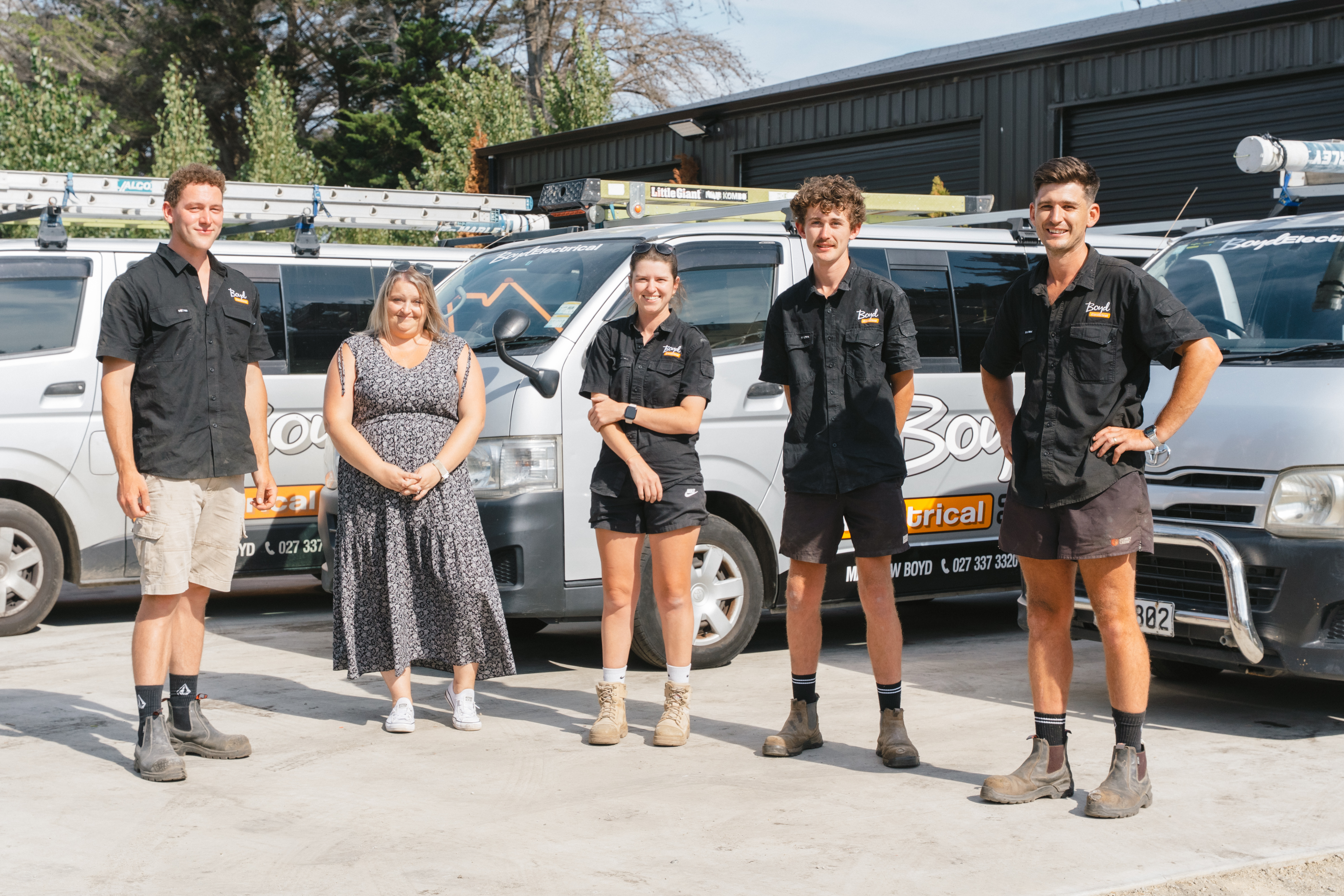 Boyd Electrical Whanganui team standing casually in front of branded vans